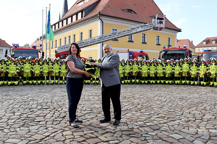  Übergabe Einsatzbekleidung durch Mandy Brußc, Mitarbeiterin der Weinhold Feuerwehrbedarf GmbH aus Kamenz, an den Bürgermeister Peter Mühle